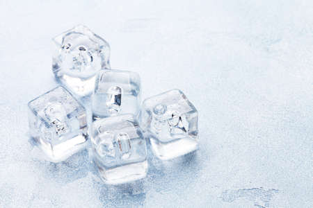 Ice cubes and water drops on stone background. With copy space