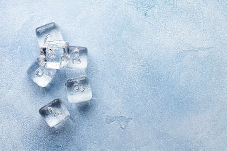 Ice cubes and water drops on stone background. Top view flat lay with copy spaceの写真素材