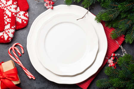 Christmas table setting with empty plate, gift box and xmas decor. Top view flat lay with copy space