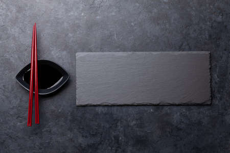 Stone plate and chopsticks for your sushi and maki. Japanese food menu backdrop. Top view flat lay...