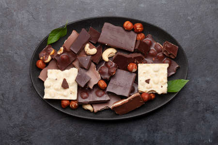 Various chocolate pieces, coffee beans and nuts plate on stone table. Top view flat lay