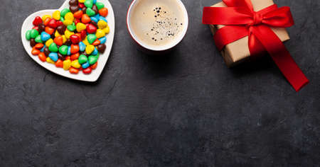 Heart shaped candies, coffee cup and gift box. Valentines day card. Top view flat lay with space for your greetingsの写真素材