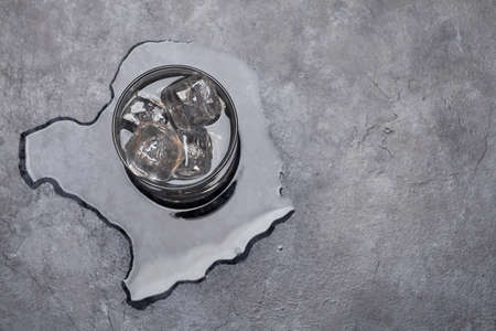 Glass of water with ice cubes on stone table. Top view flat lay with copy space