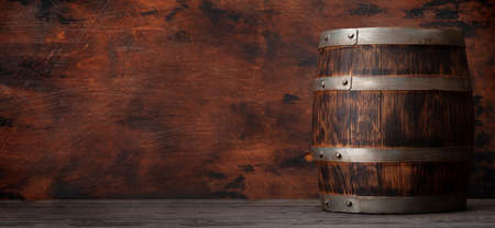 Old wooden barrel for wine or whiskey aging. In front of wooden wall with copy spaceの写真素材