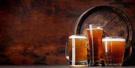 Mug and glass of light lager beer and old wooden barrel. With copy spaceの写真素材