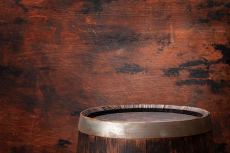 Old wooden barrel for wine or whiskey aging. In front of wooden wall with copy space for display...