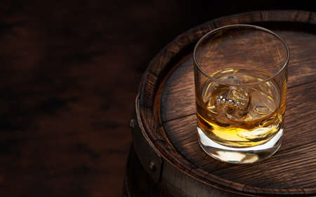 Scotch whiskey glass and old wooden barrel. With copy space