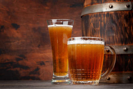 Mug and glass of light lager beer and old wooden barrel. With copy space