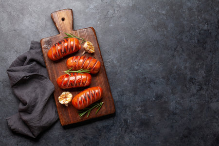 Hot grilled sausages on wooden board with garlic and rosemary. Top view flat lay with copy spaceの写真素材