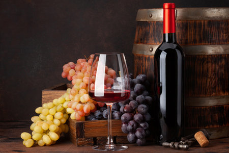 Wine bottle, grapes, glass of red wine and old wooden barrel. With copy space