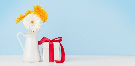 Colorful gerbera flowers and gift box over blue background. With copy spaceの写真素材