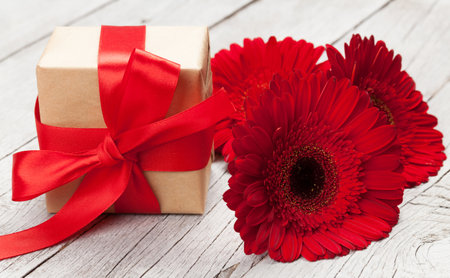 Greeting card with gerbera flowers and gift box over wood backgroundの写真素材