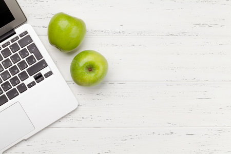 Office desk with laptop and apple fruits. Remote office and work from home concept. Top view flat lay with copy spaceの写真素材