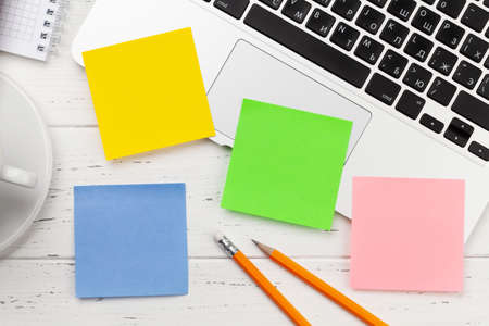 Office desk with colorful stickers, coffee and laptop. Remote office and work from home concept. Top view flat lay with copy spaceの写真素材