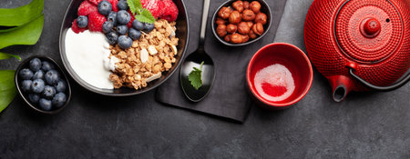 Healthy breakfast with homemade granola with yogurt and fresh berries on stone background. Top view flat layの写真素材