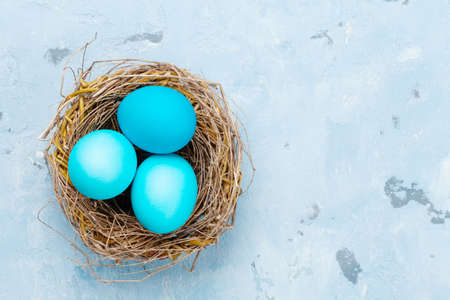 Colorful easter eggs in nest on stone background. Top view. with space for your greetings Flat lay