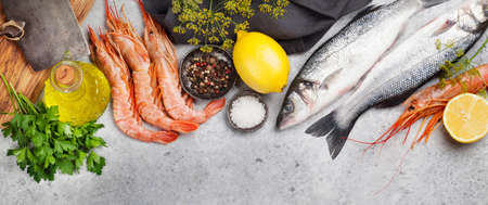 Fresh seafood. Trout fish and langostino shrimps with herbs and spices on a stone background. Top...