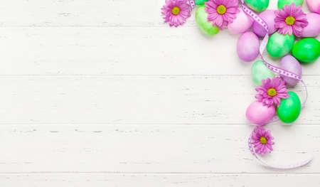 Easter greeting card with colorful easter eggs and flowers. Top view flat lay with space for your...