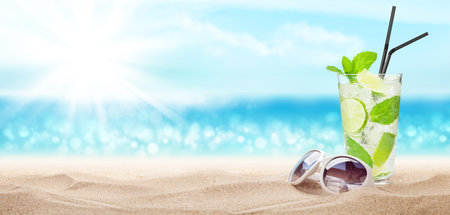 Fresh cold cocktail on tropical beach with palms and bright sand. Summer sea vacation and travel concept with copy spaceの写真素材