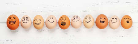 Many eggs with funny faces on wooden table. Top view flat layの写真素材