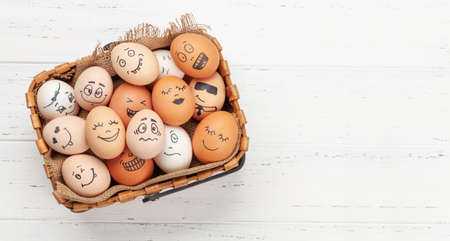 Many eggs with funny faces on wooden table. Top view flat lay with copy space
