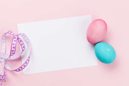Easter greeting card with colorful easter eggs on pink background. Top view flat lay with space for...