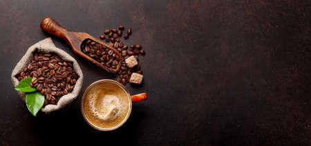 Roasted coffee beans, brown sugar and cup of hot espresso coffee. Top view flat lay with copy space