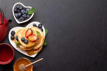 Healthy breakfast with pancakes and herbal tea. Homemade american pancakes with berries and honey. Top view flat lay with copy spaceの写真素材