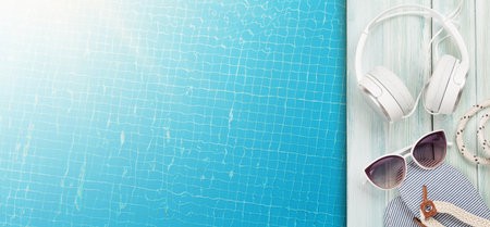 Pool and beach items, headphones and water surface of swimming pool. Travel and vacation concept. Top view flat lay with copy spaceの写真素材