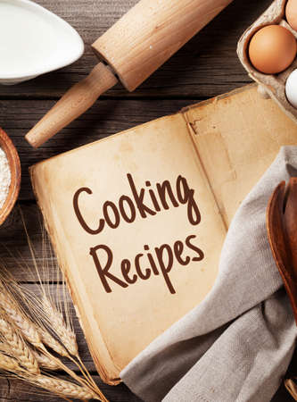 Blank vintage recipe cooking book, utensils and ingredients on wooden table. Top view flat layの写真素材