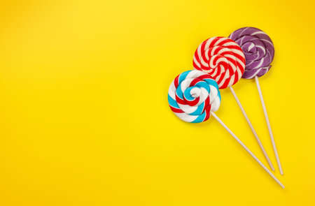 Various sweets assortment. Candy and lollipops on yellow background. Top view flat lay with copy spaceの写真素材