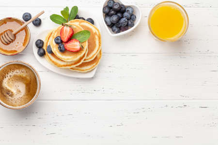 Breakfast with pancakes, orange juice and espresso coffee. Homemade american pancakes with berries and honey. Top view flat lay with copy spaceの写真素材