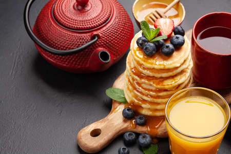 Healthy breakfast with pancakes and herbal tea. Homemade american pancakes with berries and honey. With copy spaceの写真素材