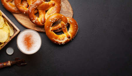 Lager beer mug, potato chips and fresh baked homemade pretzel with sea salt on stone table. Classic beer snack. Top view flat lay with copy spaceの写真素材