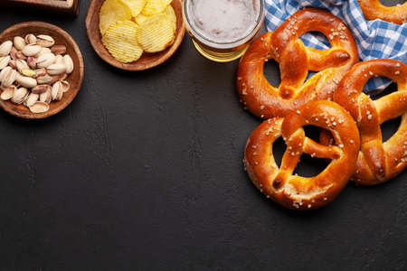 Lager beer mug, nuts, potato chips and fresh baked homemade pretzel with sea salt on stone table. Classic beer snack. Top view flat lay with copy spaceの写真素材