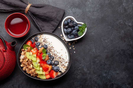 Healthy breakfast with bowl of granola, yogurt and fresh berries and herbal tea. Fitness protein meal. Top view flat lay with copy spaceの写真素材