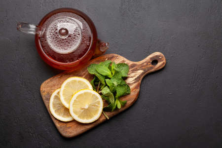 Herbal tea with mint and lemon. Teapot on stone table. Top view flat lay with copy space