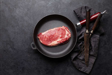 Raw beef ribeye steak on frying pan. Top view flat layの写真素材