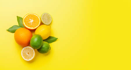 Fresh ripe citrus fruits on yellow background. Orange, lemon, lime. Top view flat lay with copy spaceの写真素材