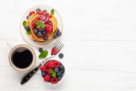 Delicious homemade pancakes with summer berries and coffee for breakfast. Top view with copy space