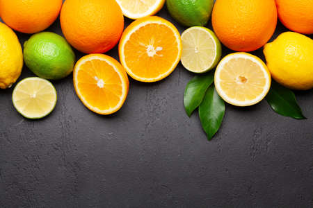 Fresh ripe citrus fruits on stone background. Orange, lemon, lime. Top view flat lay with copy spaceの写真素材