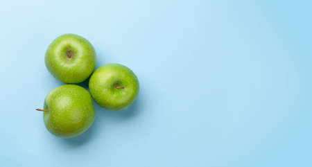 Fresh ripe green apple fruits on blue background. Top view flat lay with copy spaceの写真素材