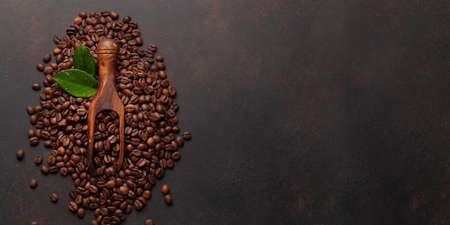 Roasted coffee beans in wooden spoon. Top view flat lay with copy space