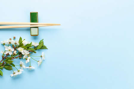 Japanese food background with cherry blossom and sushi chopsticks. Top view flat lay with copy space