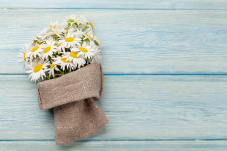 Garden camomile flowers bouquet on blue wooden table. Top view flat lay with copy spaceの写真素材