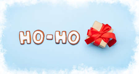 Christmas greeting card with homemade gingerbread HO-HO text and gift box. Top view flat layの写真素材