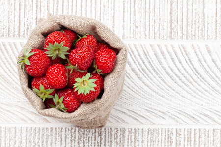 Strawberry in burlap bag. Ripe garden berries on wooden table. With copy spaceの写真素材