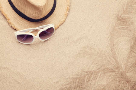 Travel vacation background concept with sunglasses, and hat on sand backdrop. Top view with copy...