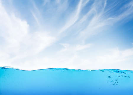 Waterline with sea underwater and blue sunny sky with cloudsの写真素材