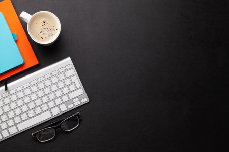 Office desk with supplies and coffee cup over black leather table. Top view flat lay with copy spaceの写真素材